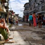 En la foto, personas esperan por algo en una calle de Cuba