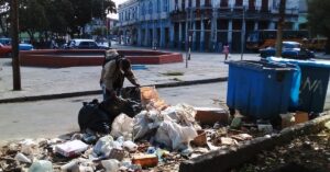En la foto, un hombre busca comida en la basura en Cuba