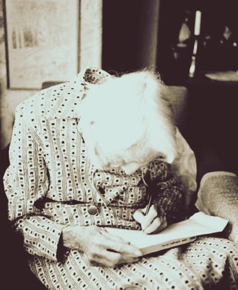 En la foto, una anciana escribe una carta