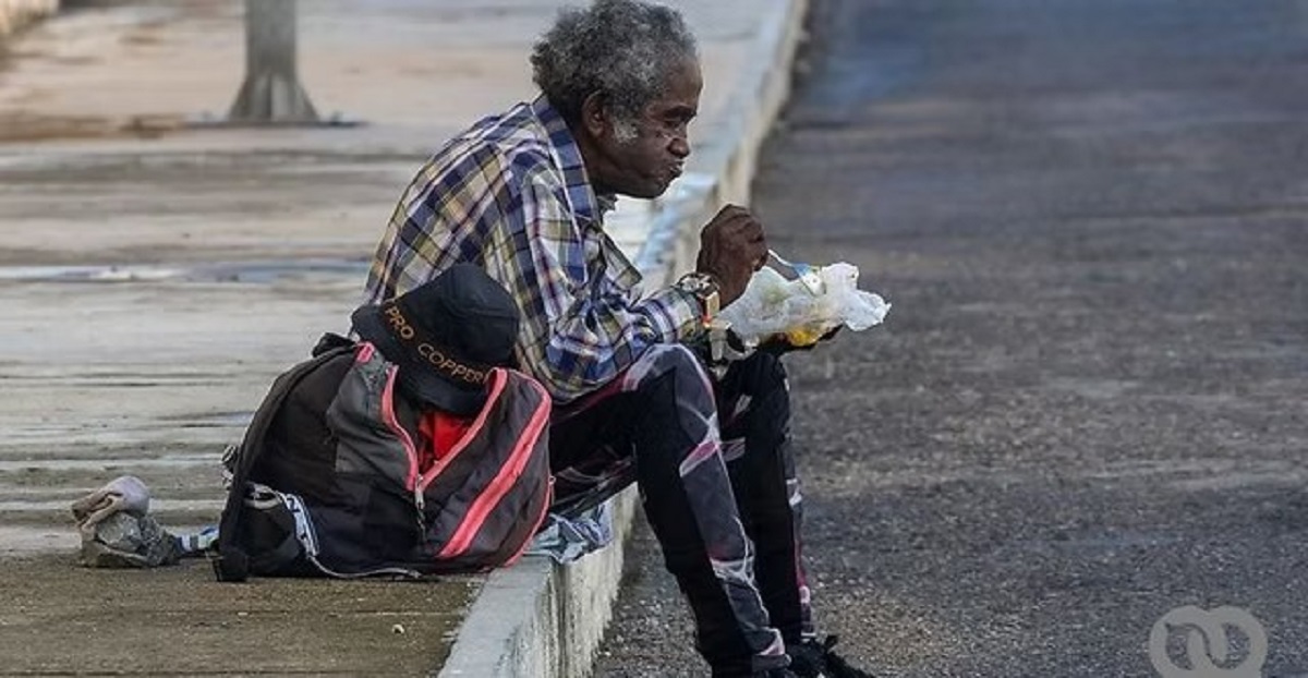 En la foto, un anciano come en la calle en Cuba