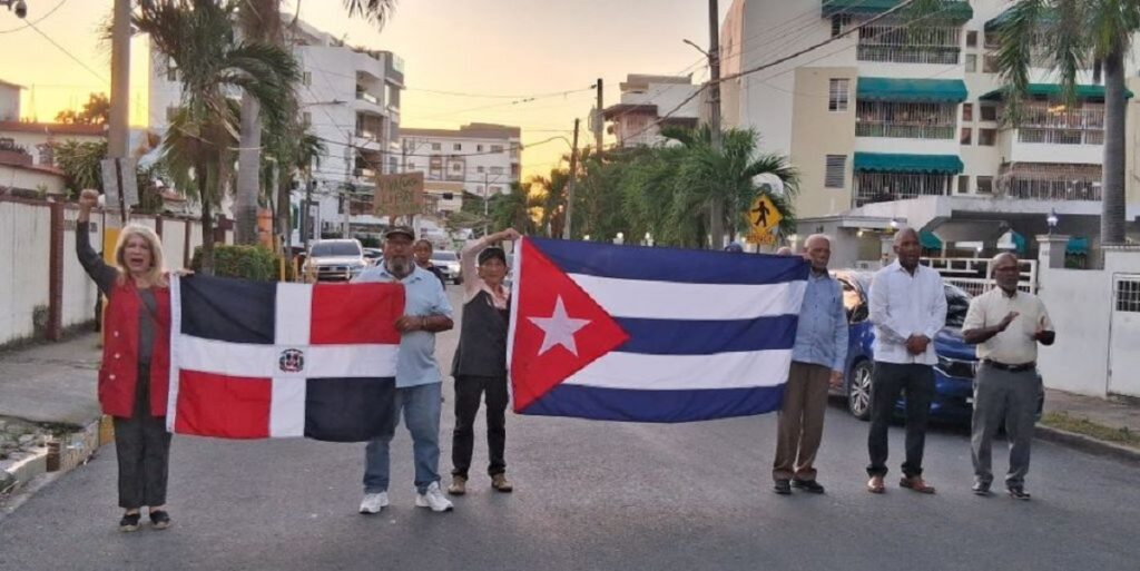 En la foto, cuatro personas respaldan a Cuba en Santo Domingo y Prensa Latina le dedica una nota