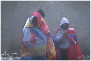 En la foto, dos personas se guarecen dela lluvia y el frío