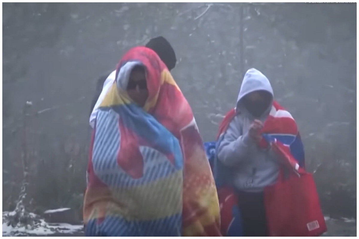 En la foto, dos personas se guarecen dela lluvia y el frío