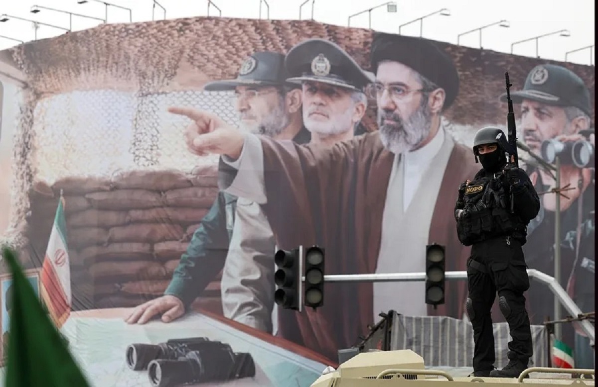 En la foto, un miembro de las fuerzas de seguridad iraníes frente a una valla en la que aparecen el líder supremo iraní, Mojtaba Jamenei, y varios mandos militares iraníes, durante una concentración con motivo del Día Internacional de Al-Quds en Teherán, Irán, el 13 de marzo de 2026