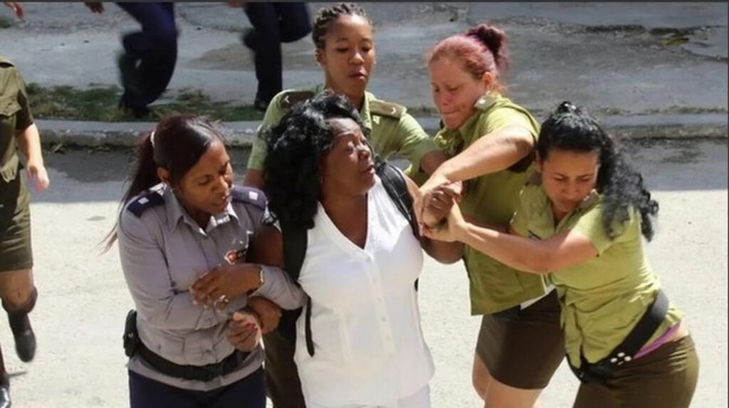 En la foto, mujeres policías reprimen a una dama de blanco
