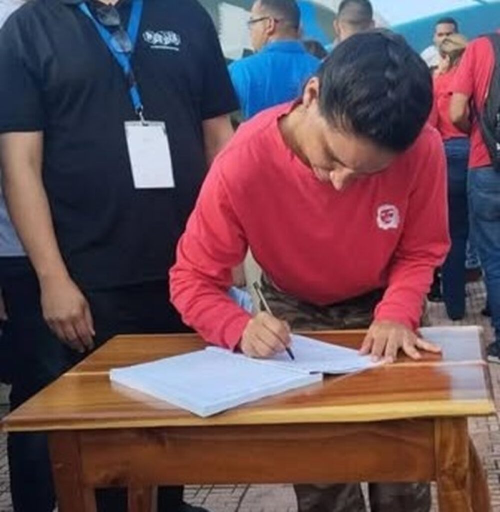 En la foto, una mujer firma un documnto en el que se compromete a defender al castrismo