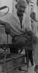 En la foto, un limpiabotas al lado de su sillón