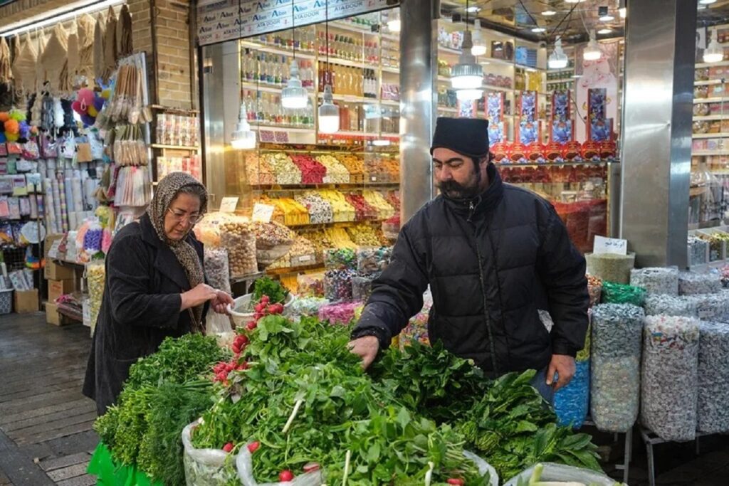 En la foto, una mujer compra verduras en un mercado en Teherán