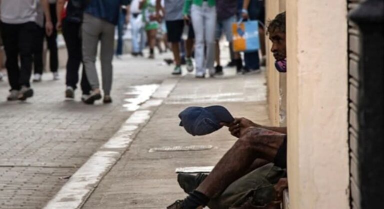 En la foto, un mendigo extiende una gorra en una calle de Cuba