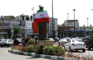 En la foto, La bandera nacional de Irán rodea una estatua en una calle de Teherán