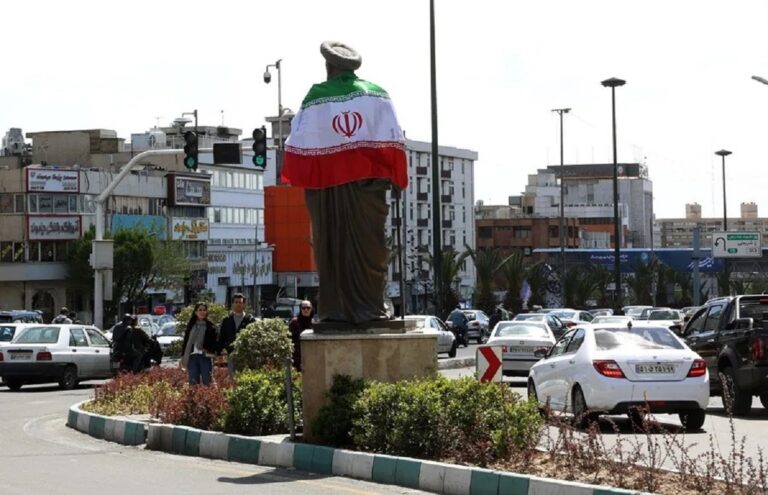 En la foto, La bandera nacional de Irán rodea una estatua en una calle de Teherán