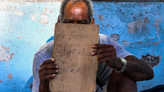 En la foto, un anciano pide algo de comer en La Habana