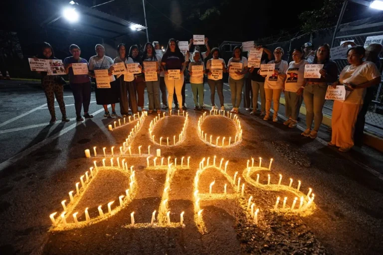 En la foto, Personas sostienen carteles durante una vigilia afuera de la cárcel El Rodeo I este sábado, en Guatire
