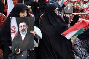 En la foto, Una mujer iraní vestida con un chador negro sostiene un cartel del líder supremo iraní, el ayatolá Mojtaba Khamenei