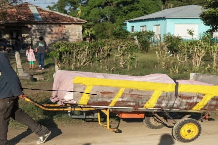En la foto, un hombre lleva un ataud en una carretilla