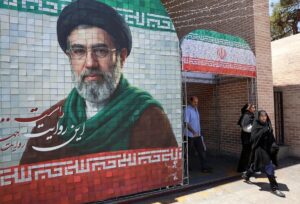 En la foto, Iraníes pasan junto a una imagen del líder supremo iraní, el ayatolá Mojtaba Jamenei, en una calle de Teherán