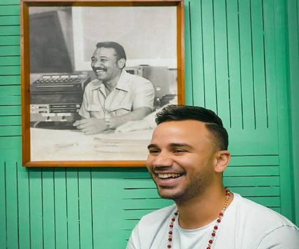 En la foto, el hijo de Juan Almeida ante una foto de su padre