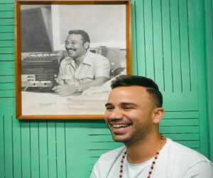 En la foto, el hijo de Juan Almeida ante una foto de su padre