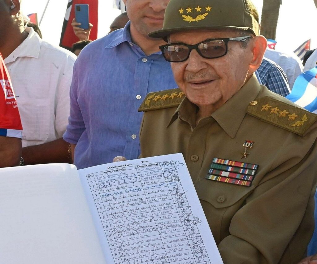 En la foto, Raúl Castro presenta un libro con las firmas