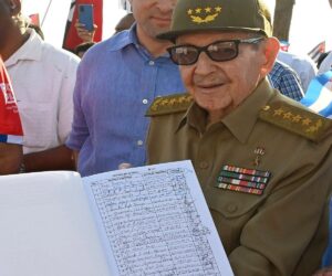 En la foto, Raúl Castro presenta un libro con las firmas