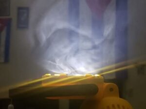 En la foto, la luz de una linterna atraviesa el humo y deja ver una bandera cubana al fondo