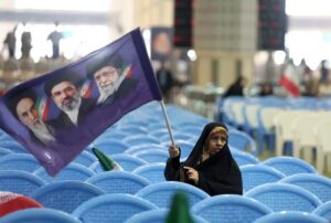 En la foto, Una mujer iraní sostiene una bandera con los retratos de los difuntos líderes supremos y el actual, en una ceremonia en memoria de los caídos en la guerra con EE.UU. e Israel, celebrada el domingo en la mezquita de Mosallah en Teherán.