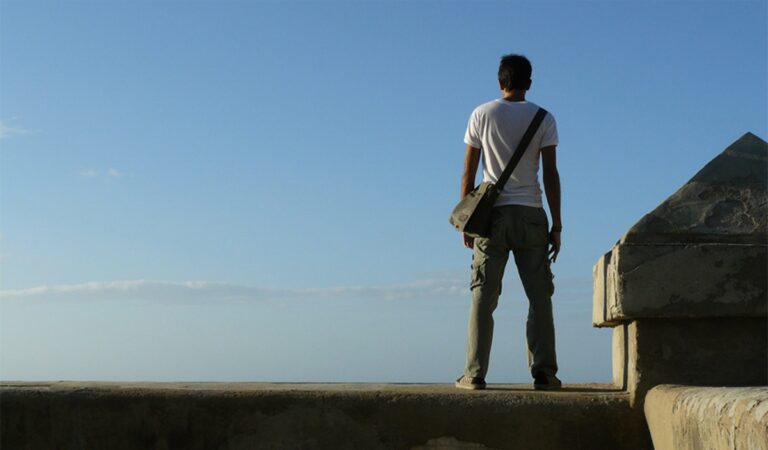 En la foto, un hombre de pie sobre el malecón de La Habana