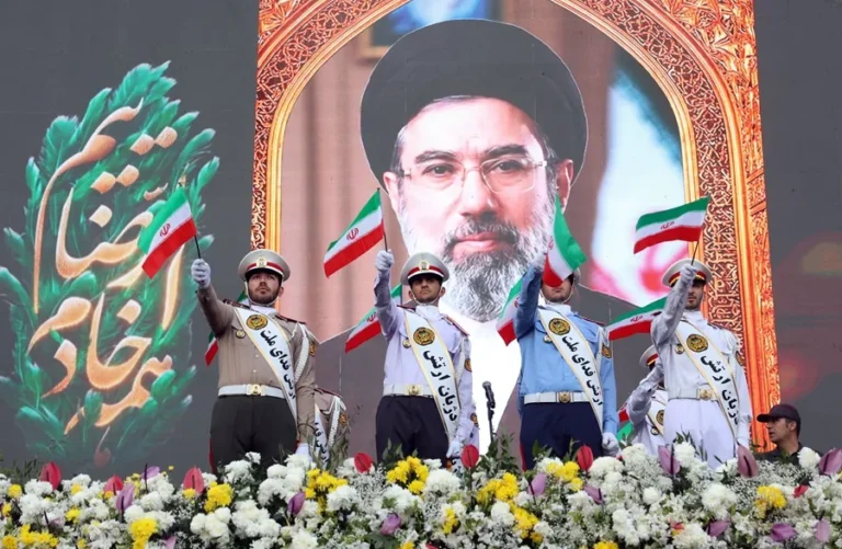 En la foto, Miembros del ejército iraní ondean banderas nacionales frente a un cartel del líder supremo iraní, el ayatolá Mojtaba Khamenei