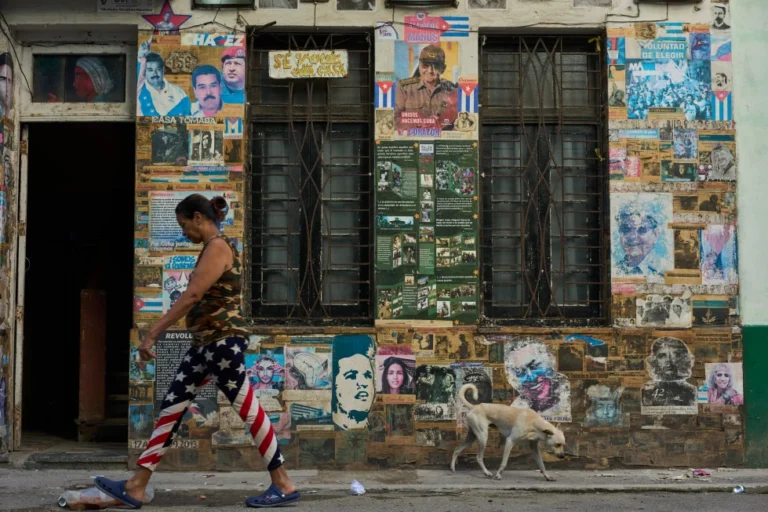 La estrategia de Trump en Cuba es similar a la que usó en Venezuela, pero hay diferencias clave 2 En la foto, una mujer con un pantalón con la bandera de EEUU camina ante fotos con símbolos del castrismo