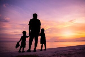 En la foto, un padre con sus hijos, en silueta