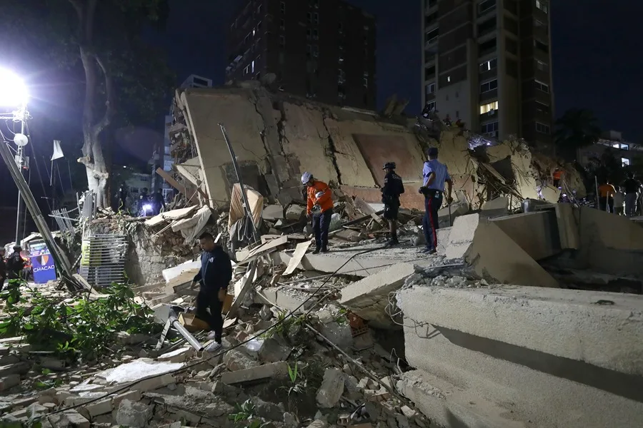 En la foto, Integrantes de cuerpos de emergencia buscan víctimas este miércoles en una edificación colapsada, en Caracas
