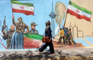 En la foto, Una mujer camina delante de un mural en Teherán