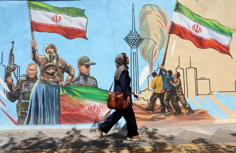 En la foto, Una mujer camina delante de un mural en Teherán