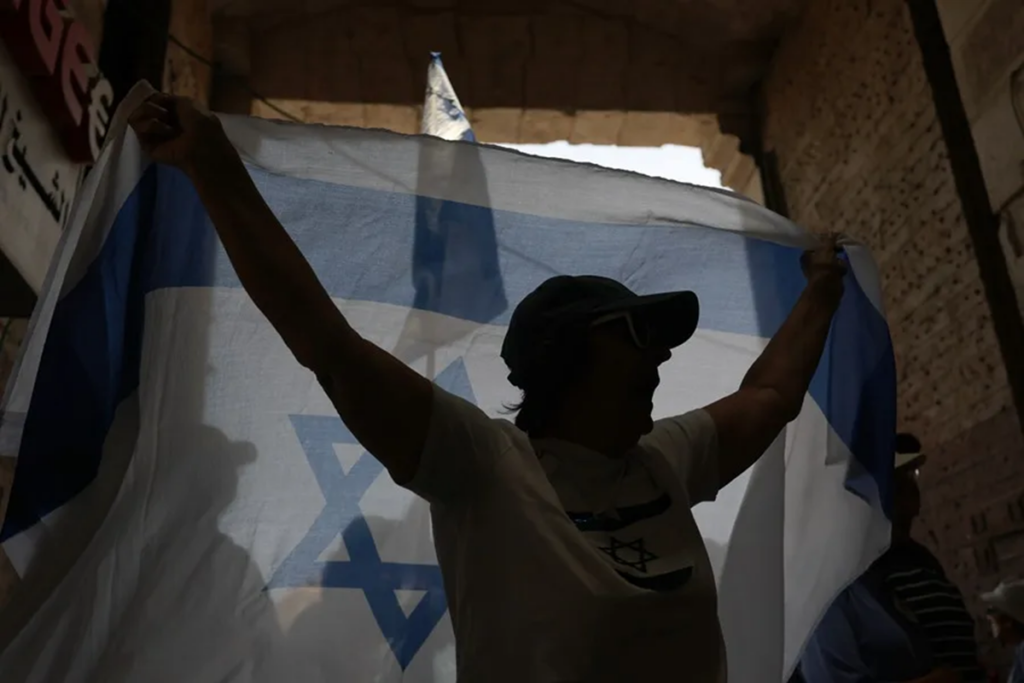 en la foto, un hombre sostiene una bandera de Israel