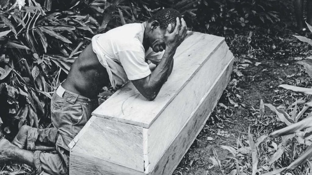 En la foto, un hombre llora sobre un ataúd