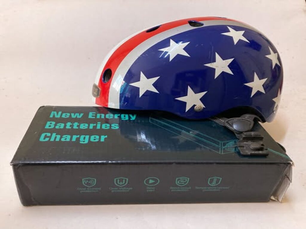 En la foto, un casco de moto y un cargador eléctrico para motos
