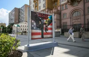 En la foto, Cartel en una calle de Moscú en el que aparece la mano de una persona con un traje con los colores de la bandera ucraniana (d) esposada a otra persona, frente a la embajada de Estados Unidos