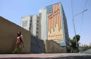 En la foto, Una mujer iraní camina cerca de un mural antiamericano en una calle de Teherán, Irán