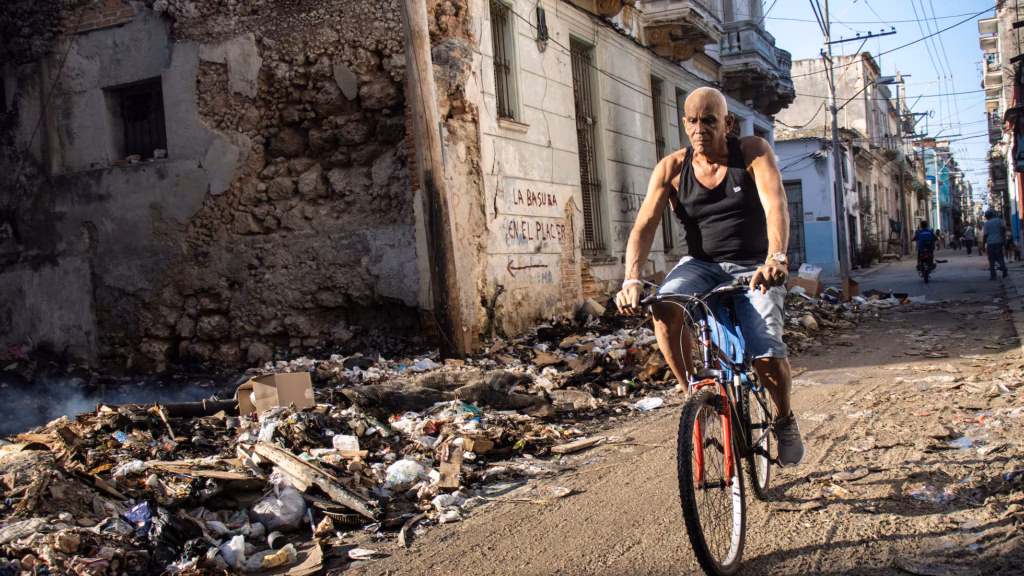 La Revolución y la tragedia 2 En la foto, un hombre pasa en bicicleta ante un enorme basurero en Cuba