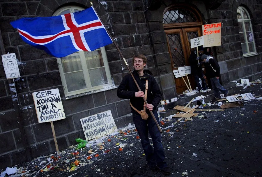 En la foto, Un joven sostiene una bandera islandesa durante una protesta