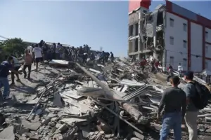En la foto, Personas caminan sobre los escombros de un edificio colapsado este lunes, en Cali (Colombia)