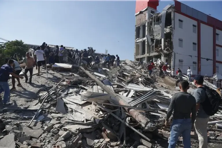 En la foto, Personas caminan sobre los escombros de un edificio colapsado este lunes, en Cali (Colombia)