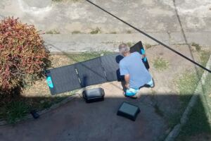 En la foto, un hombre extiende sus paneles solares en un jardín para cargar las baterías
