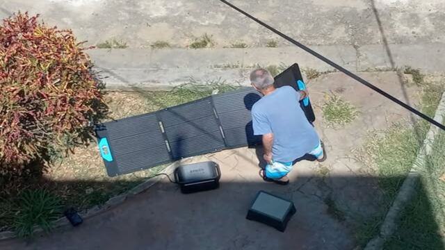 En la foto, un hombre extiende sus paneles solares en un jardín para cargar las baterías