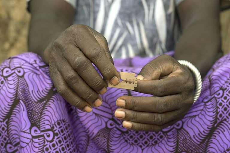 En la foto, una mujer africana con una de las cuchillas que usan para mutilar a las niñas