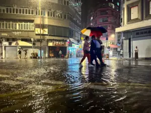 En la foto, personas compartiendo un paraguas en una calle inundada, en Hong Kong (China)