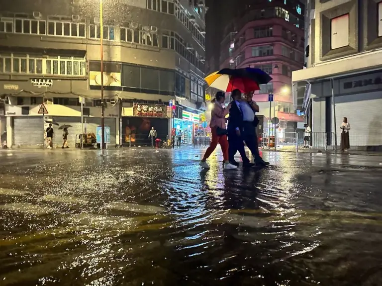En la foto, personas compartiendo un paraguas en una calle inundada, en Hong Kong (China)
