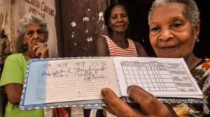 En la foto, una anciana muestra una libreta de racionamiento