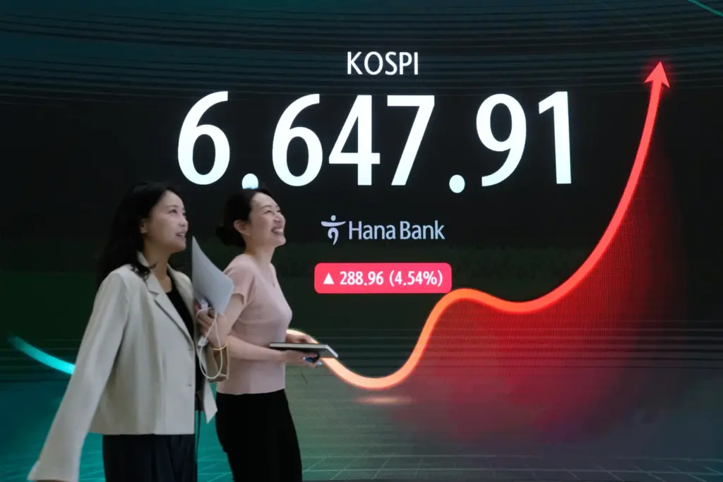 Operadores de divisas pasan junto a una pantalla que muestra el Indice Compuesto de Precios de la Bolsa de Corea