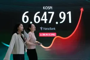 Operadores de divisas pasan junto a una pantalla que muestra el Indice Compuesto de Precios de la Bolsa de Corea